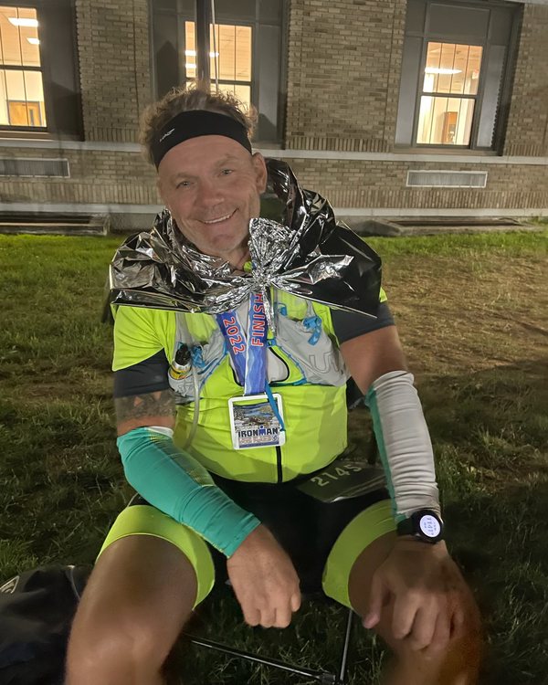 Will Power exhausted and smiling in a foil blanket after Ironman Lake Placid 2022